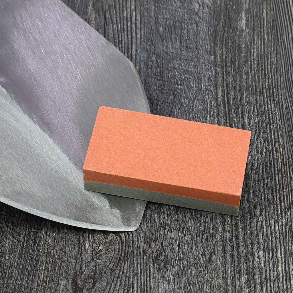 Sneeboer Block Whetstone Sharpener - on garden spade blade